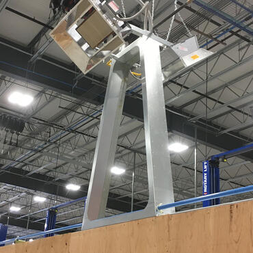 High-intensity infrared heaters hung by chain above equipment in a factory